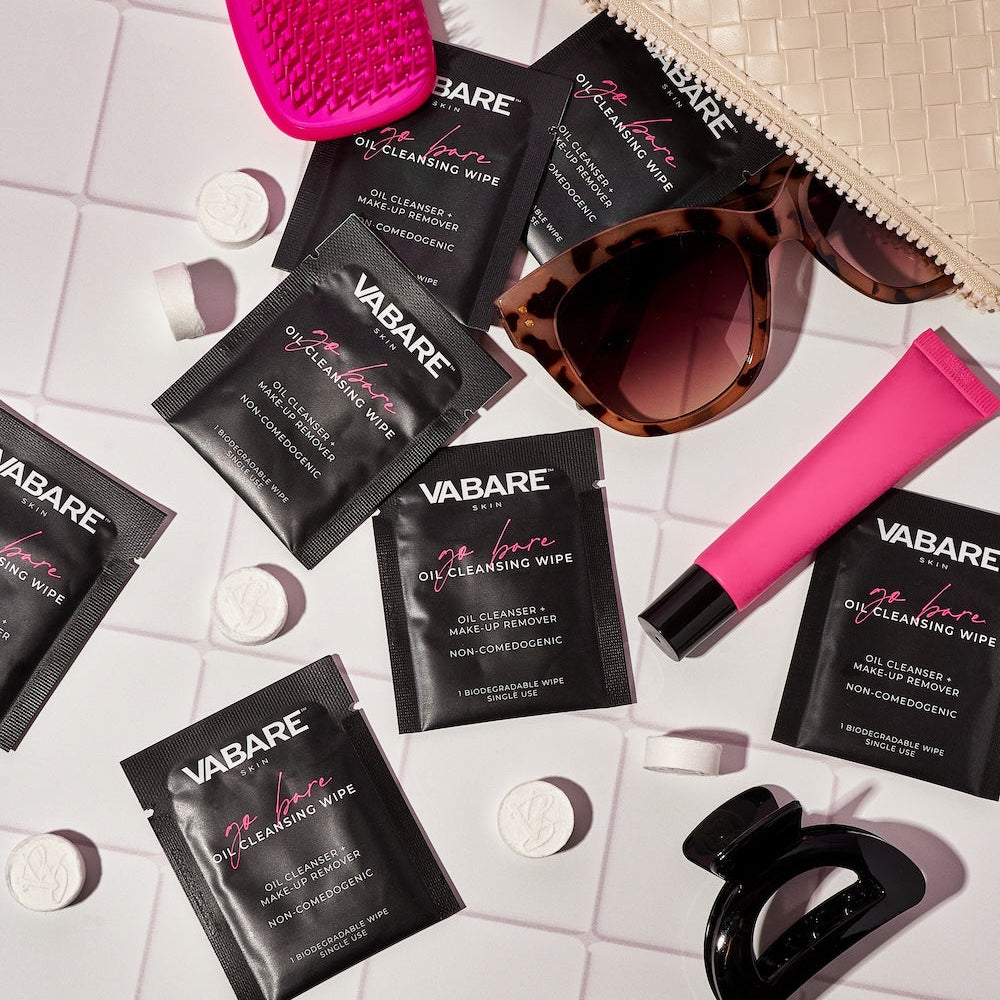 Vabare skincare products including oil cleansing wipes and a pink lip gloss tube on a light background